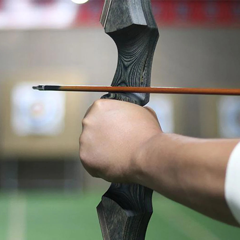 Close-up of a shooter using a hunting recurve bow with an arrow nocked for aim