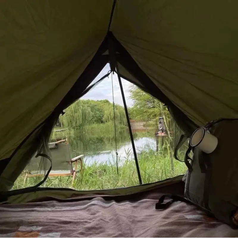 Military camping tent with scenic lake view from inside