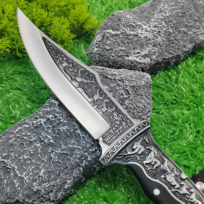 Intricately designed stainless steel hunting knife with a decorative handle on textured rocks