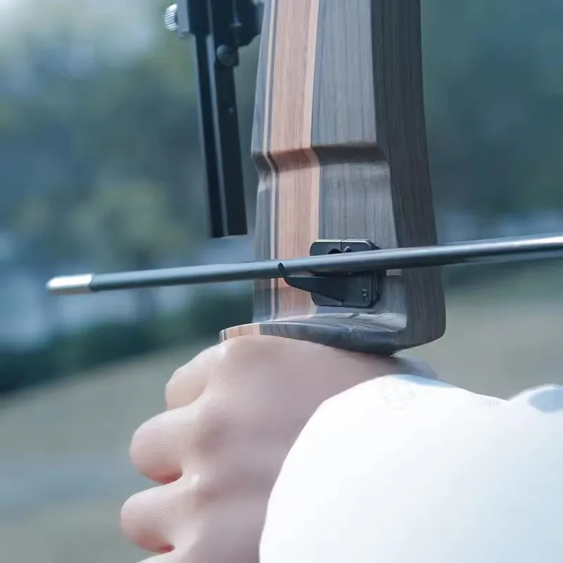 Close-up of a hand holding a wood recurve bow showcasing its grip and design for archery enthusiasts