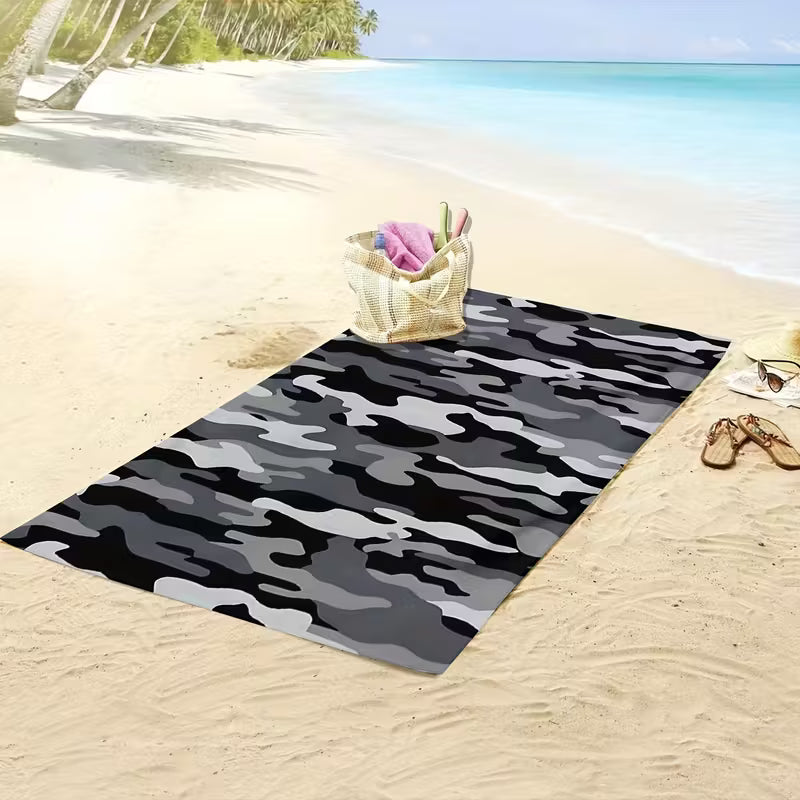 Camouflage beach towel spread on sandy shore, perfect for outdoor relaxation and beach adventures