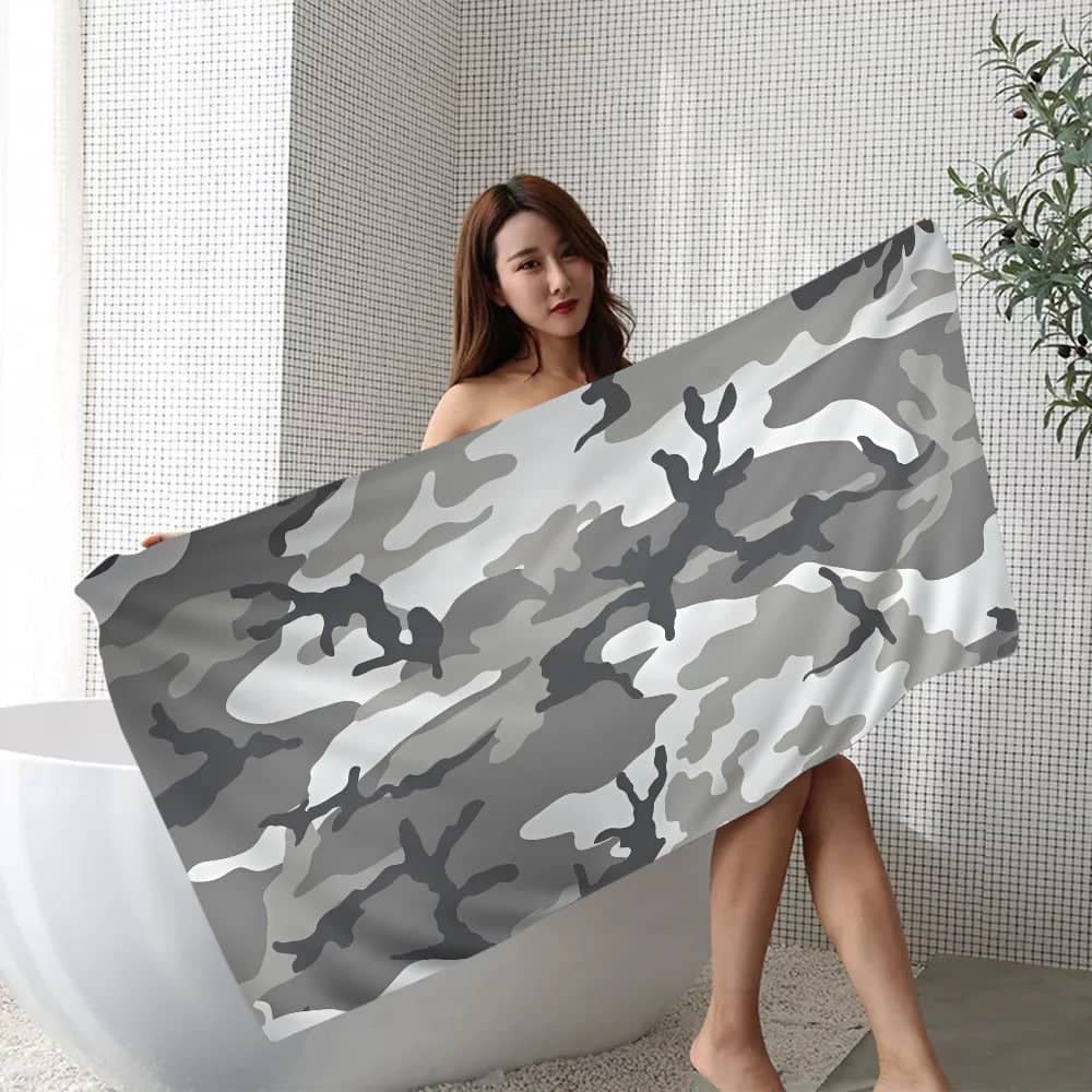Woman holding a camouflage beach towel with a chic gray pattern, ideal for outdoor activities