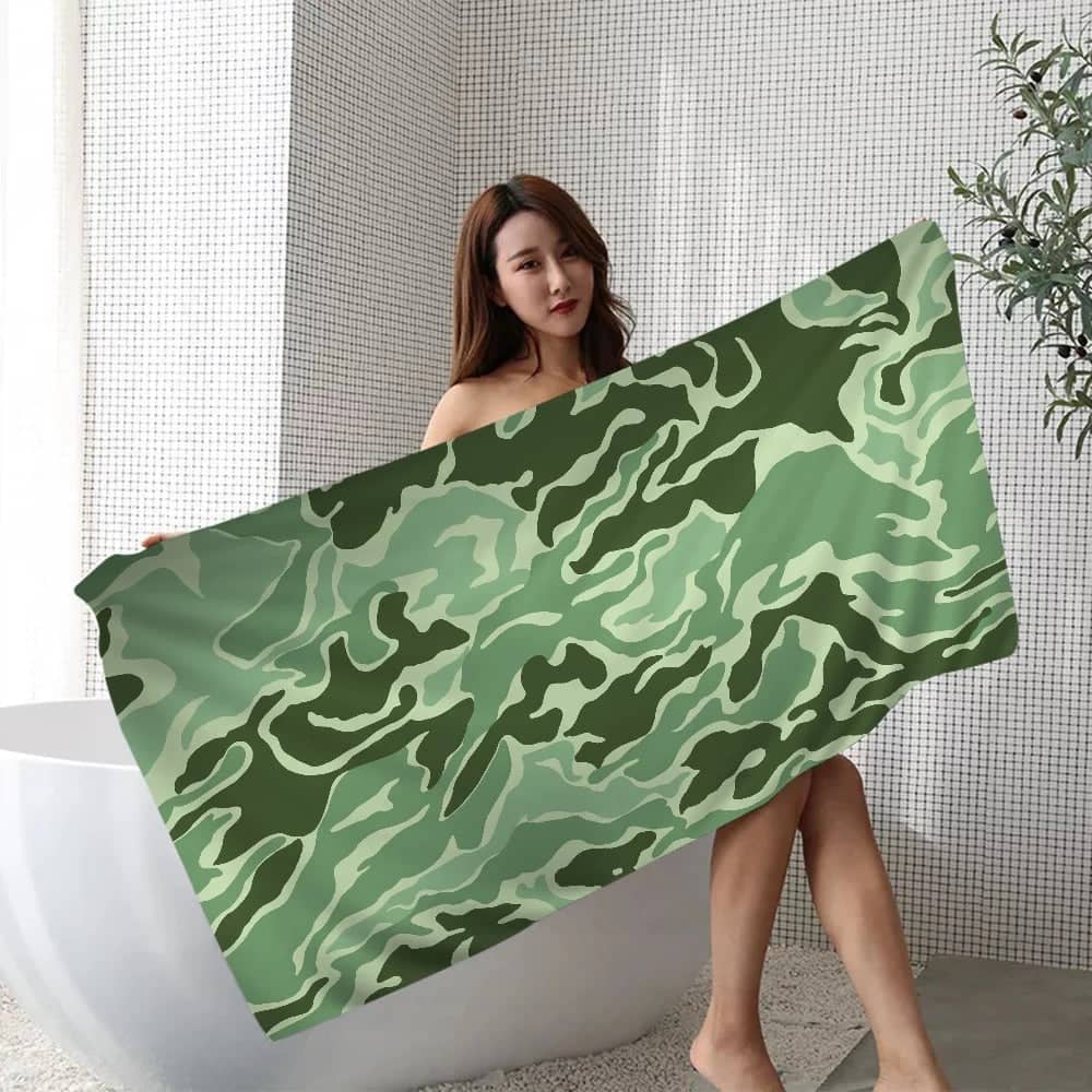 Camouflage beach towel displayed by a person in a modern bathroom setting