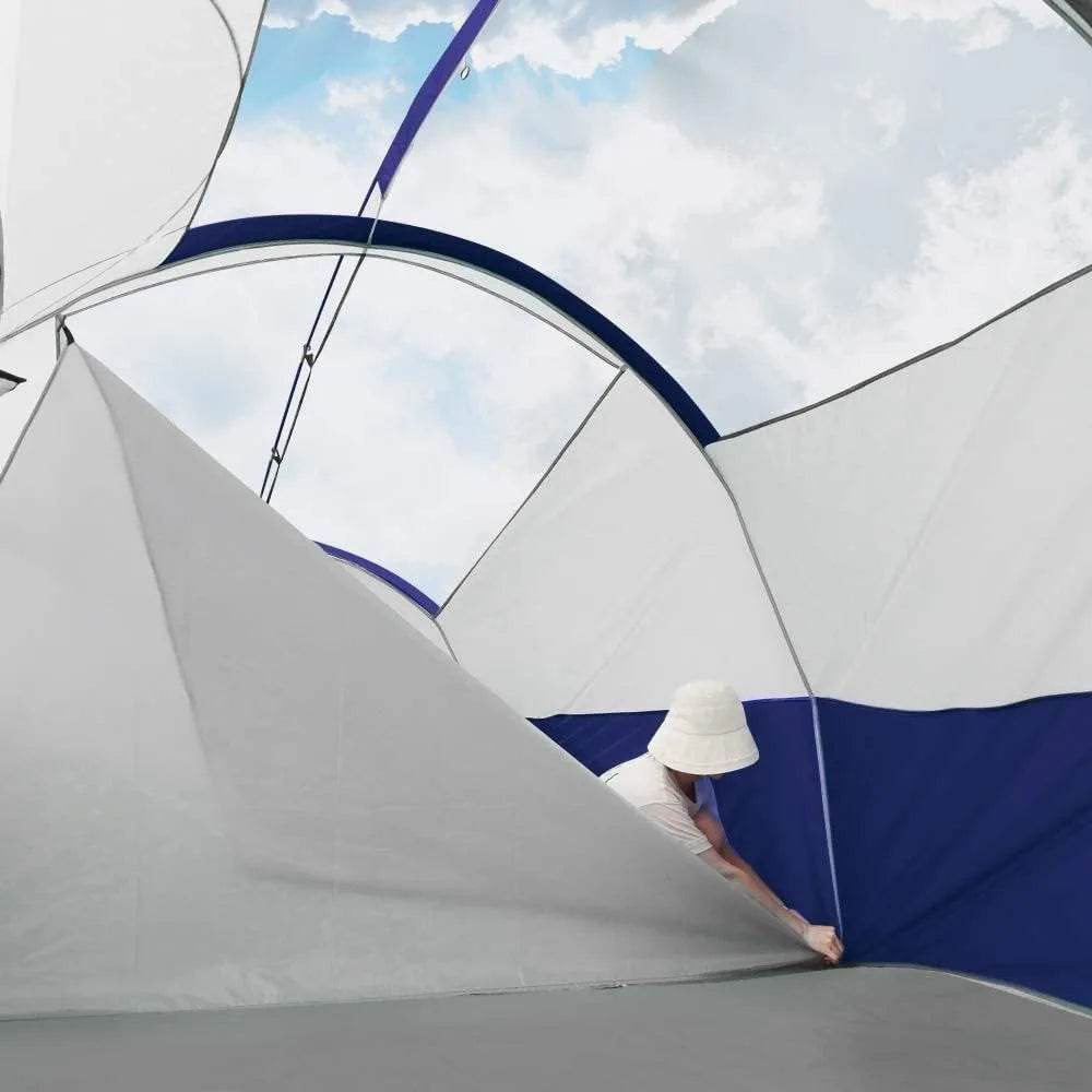 Inside view of a spacious double layer family camping tent with a person adjusting the interior, bright sky outside