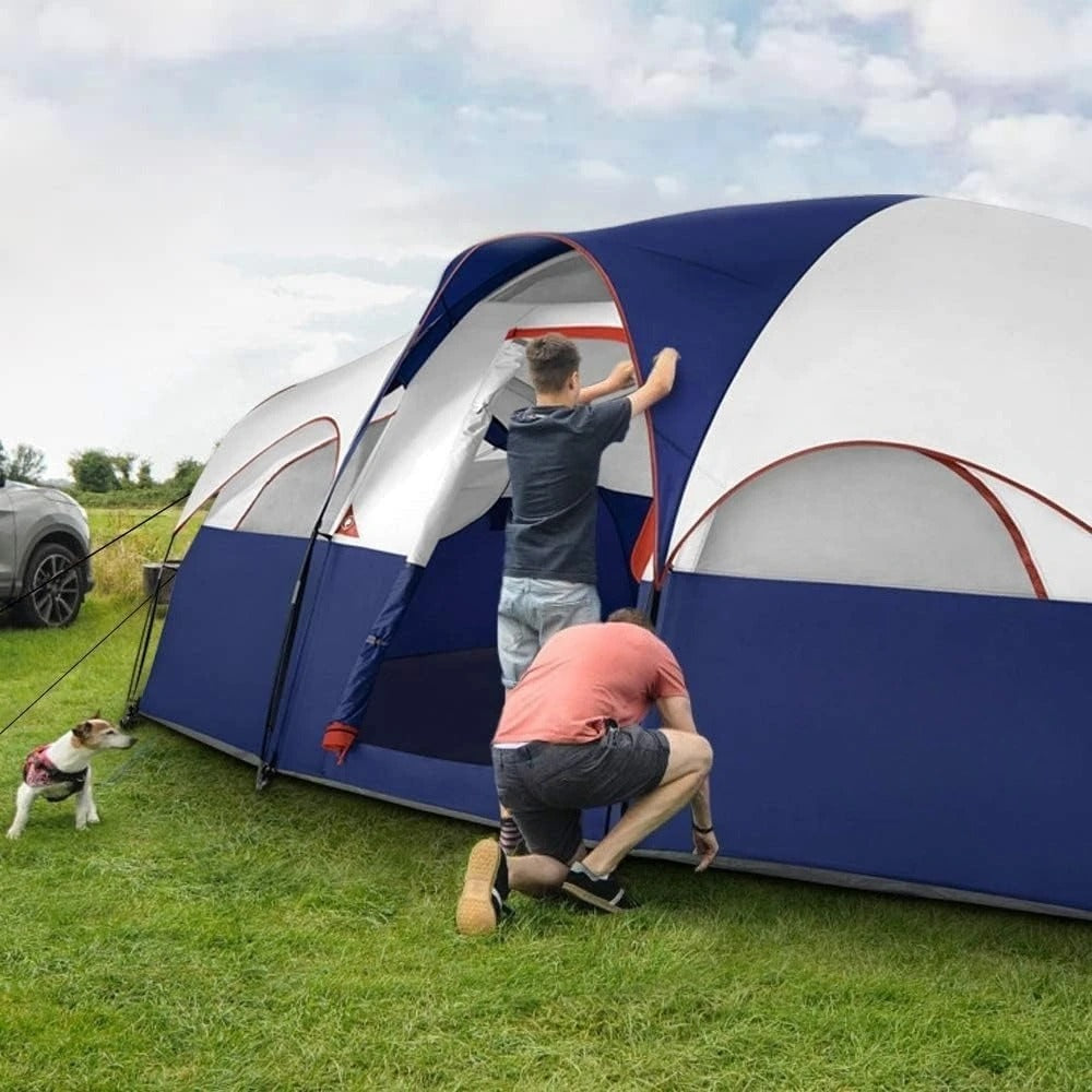Two people setting up a double layer family tent in a grassy outdoor area with a dog beside them