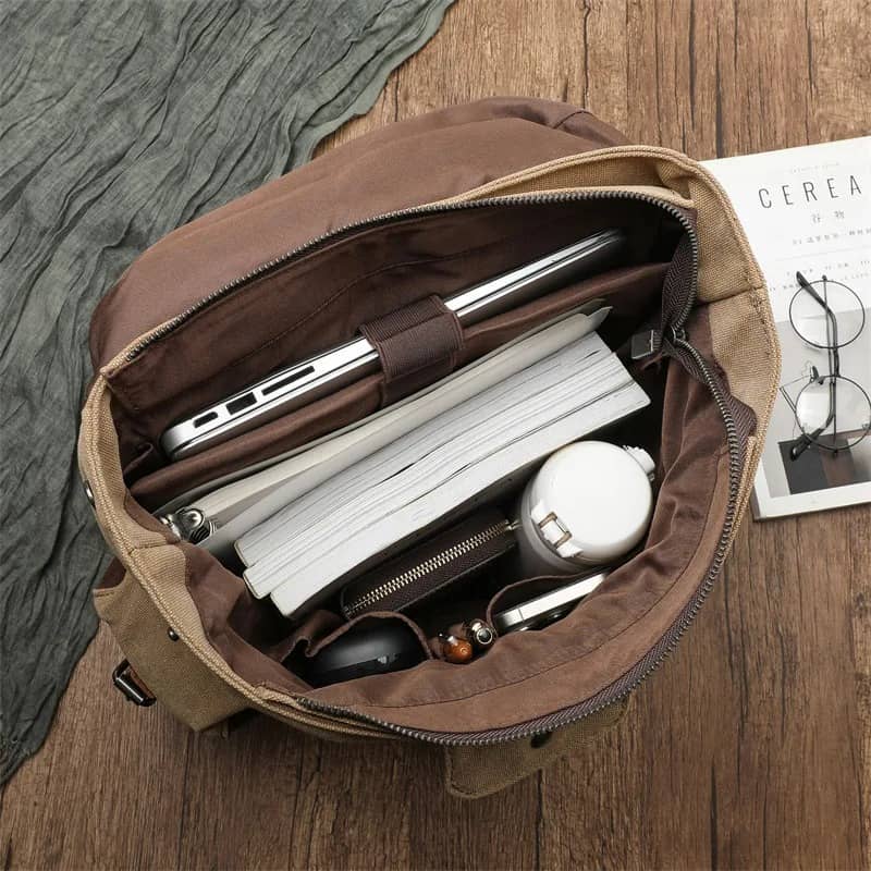 Brown leather satchel bag with items inside on a wooden surface