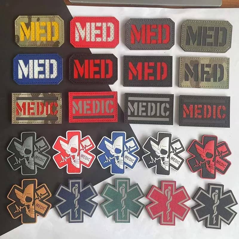 A collection of tactical medical patches featuring 'MED' text and Star of Life symbols in various colors and patterns, arranged on a black and white background.