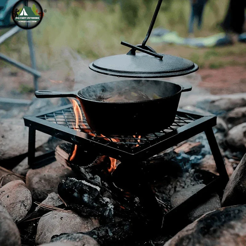 Outdoor bonfire grill with cooking pot over an open fire on a rocky surface