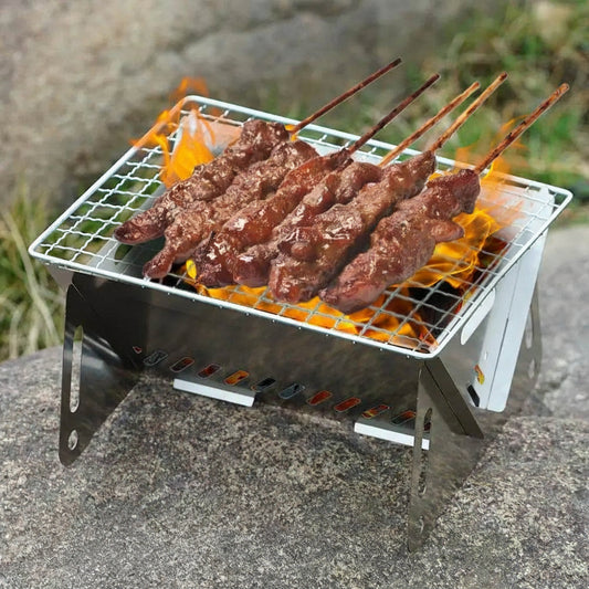 Portable folding camping grill with skewers cooking over flames