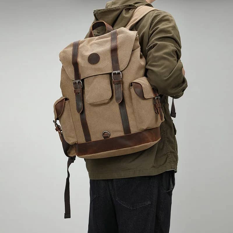 Person wearing a beige backpack with brown straps on a gray background