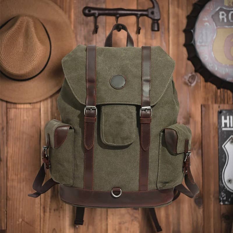 Green backpack with brown straps on a wooden background
